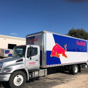 Red Bull semi truck in warehouse parking lot.