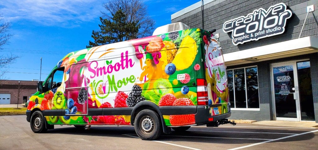 A food truck labeled "Smooth Move" with fresh fruits and vegetables parked in front of a store.