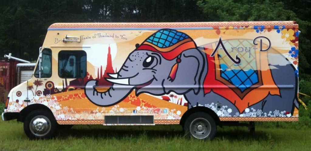 Indian food truck with a orange and white wrap with an elephant on it.