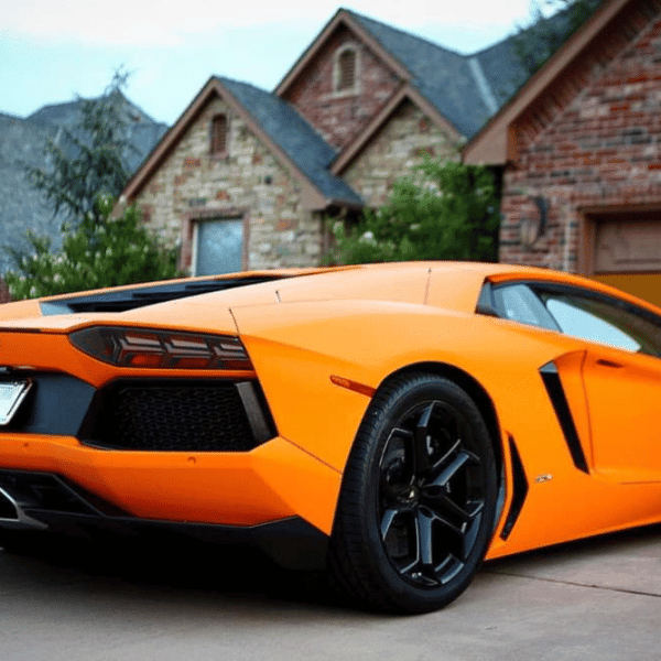 Orange Lamborghini with car wrap parked in front of a house.