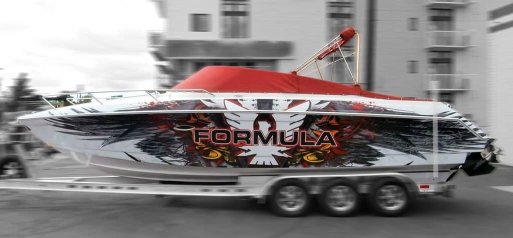 A boat with a "Formula" wrap parked on the street, showcasing a large design on its exterior.