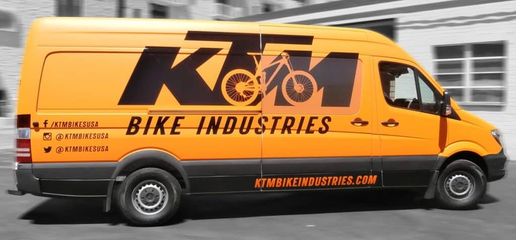 A yellow van wrapped with "KTM bike industries" text, showcasing the brand's identity and vibrant design.
