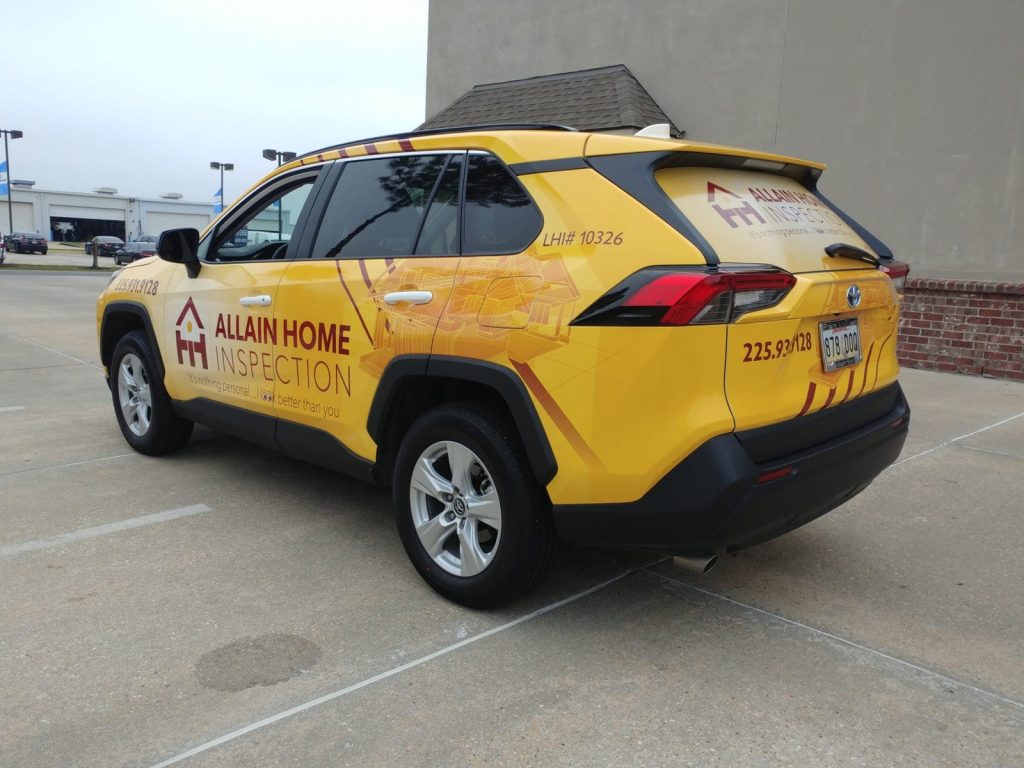 A yellow SUV with a vinyl wrap parked in a parking lot, showcasing its vibrant color and modern design.
