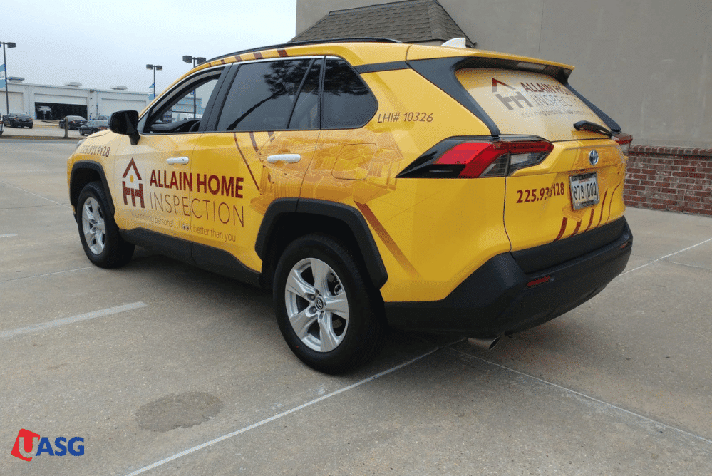 A yellow SUV featuring a vinyl wrap with the words "All Home Construction" prominently displayed on its side.