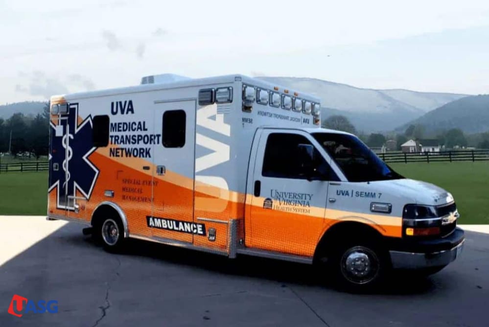 White and orange UVA Medical Transport Network vehicle with a clean professional wrap parked in a scenic rural setting.